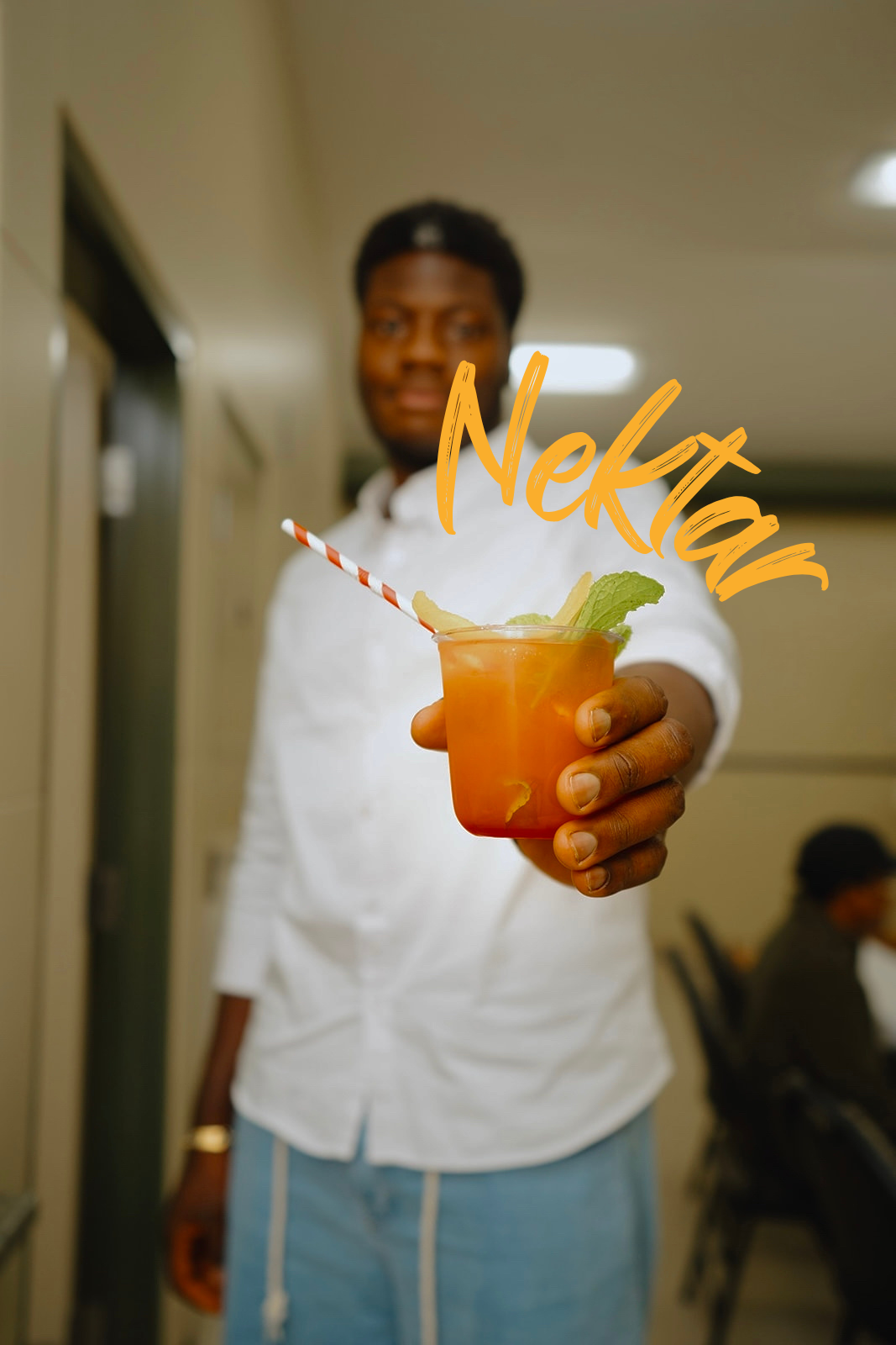 Host offering an orange Nektar mocktail garnished with mint, citrus and ginger
